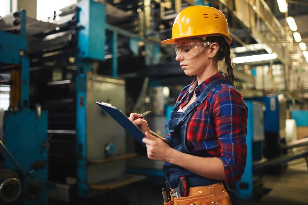 A worker in protective equipment checking a production line